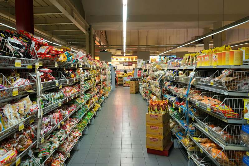 Woman reviewing affordable healthy groceries from 99 Cents Only Store with notebook and reusable bags